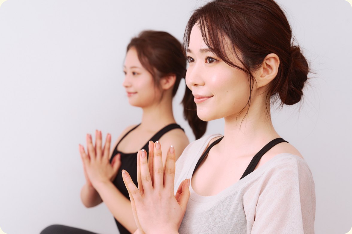 ヨガのポーズで合掌する二人の女性